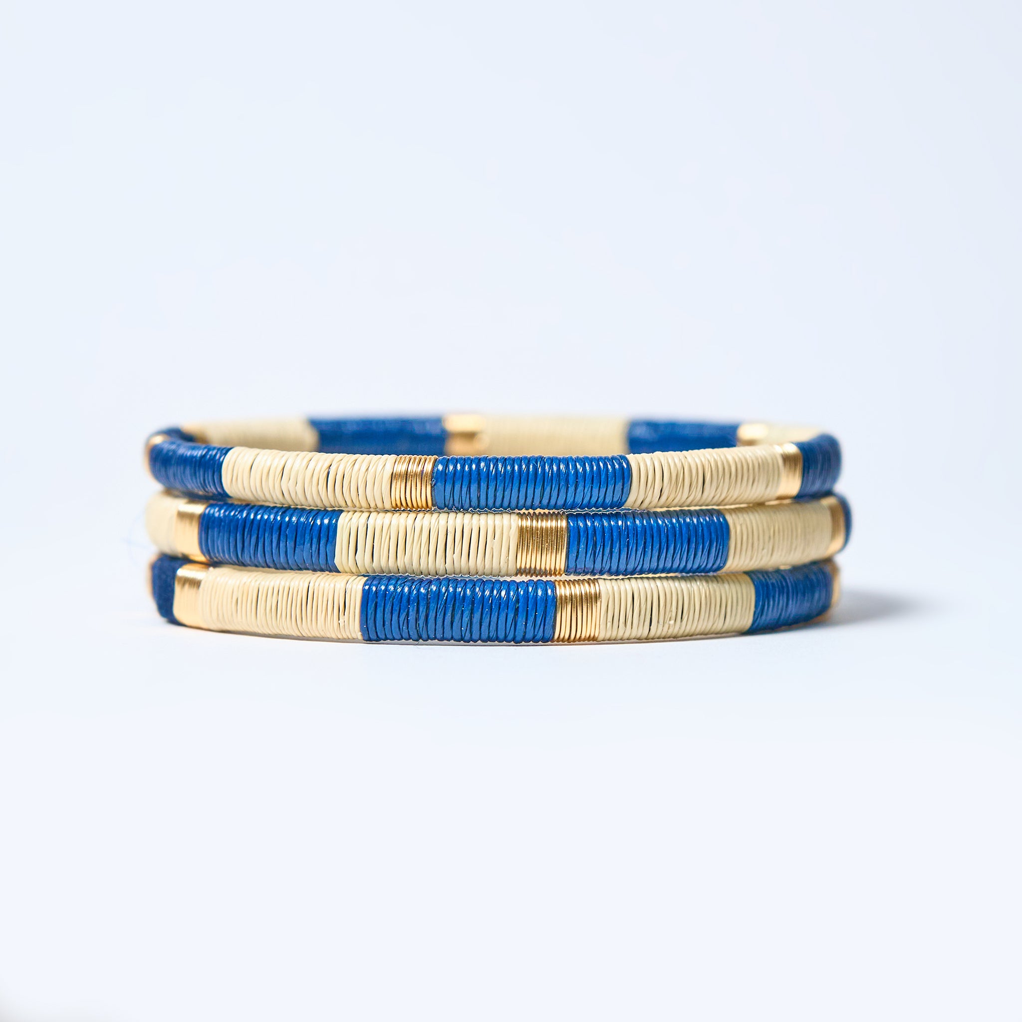 Set of handmade striped bracelets in cream, blue and gold