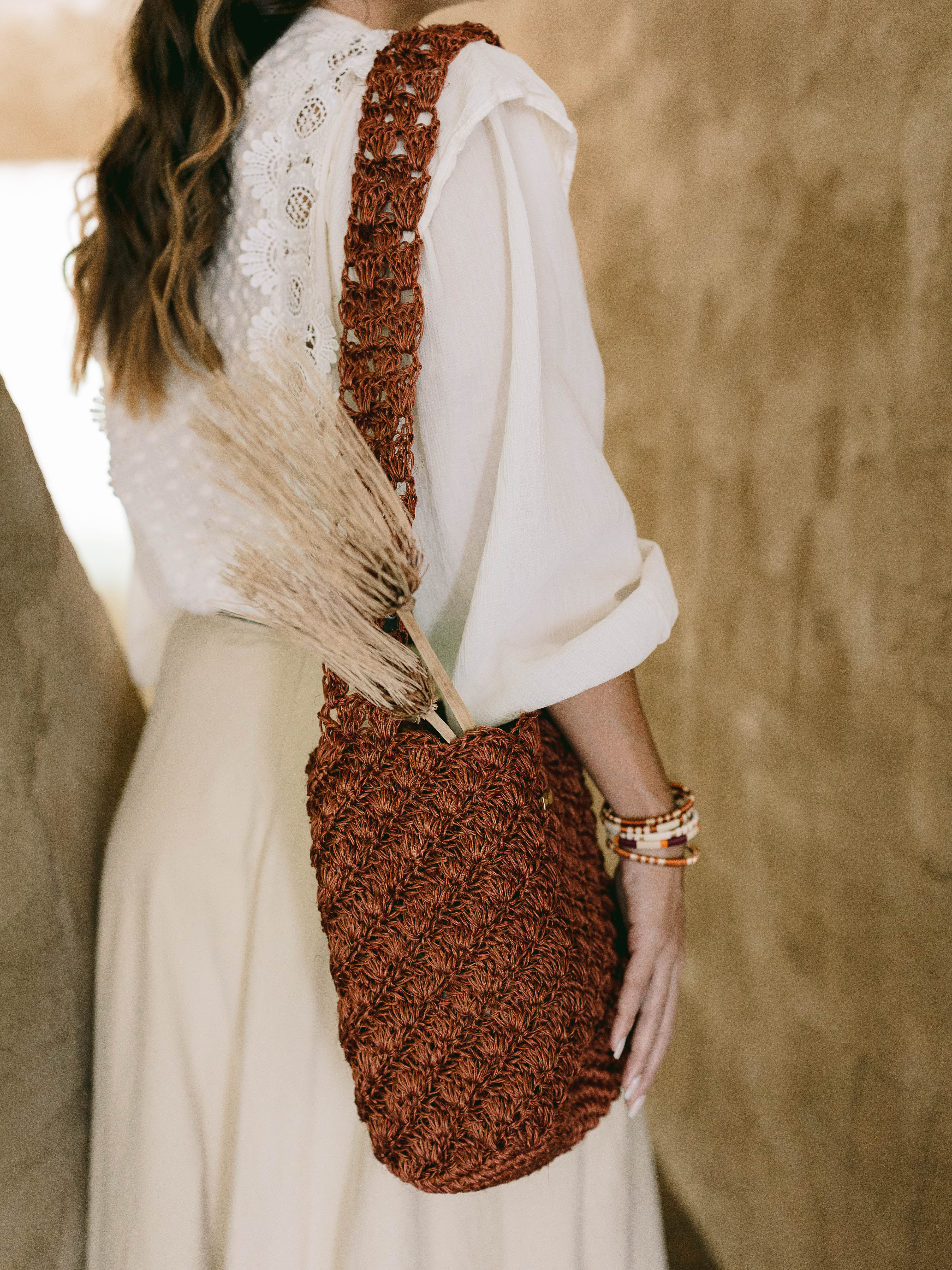 Person holding a brown handmade oda nova woven bag with a blurred background